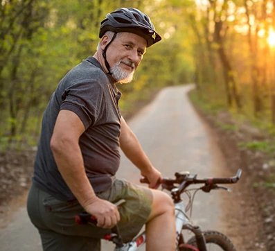 man in 60's riding bike through park