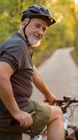 man in 60's riding bike through park