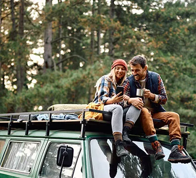 Couple camping, looking at a phone
