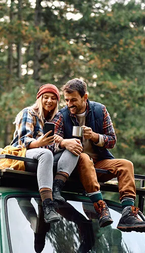 Couple camping, looking at a phone