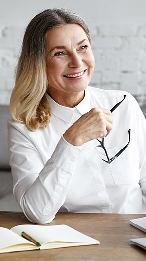 happy senior woman taking reading glasses off